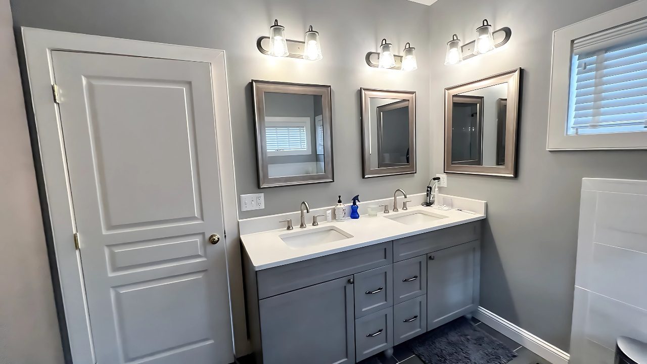 Berlin Vanity Replacement Double vanity installation with brushed nickel fixtures and framed mirrors in a remodeled Berlin, CT bathroom featuring soft gray walls and modern lighting.