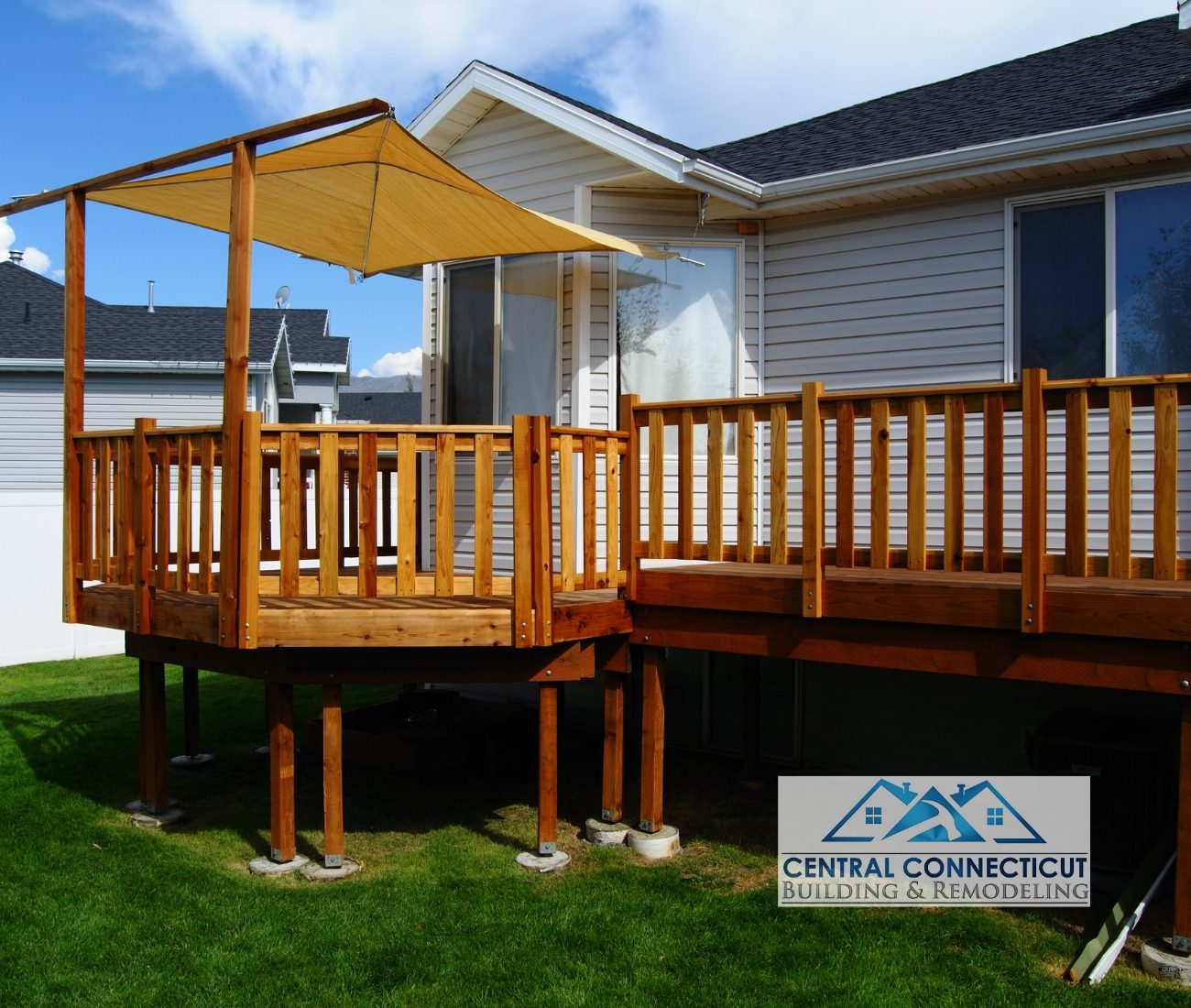 Deck Build in Berlin on Southington Road Newly built elevated wooden deck with railing and sunshade canopy, attached to a residential home in Berlin, CT — designed and constructed by Central Connecticut Building & Remodeling.
