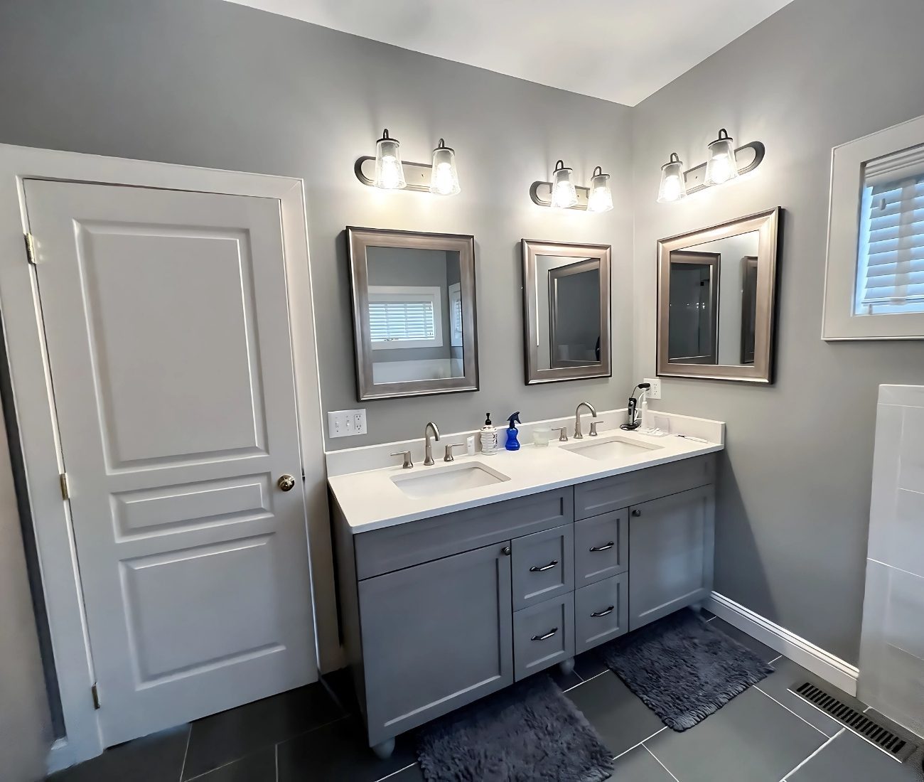 bathroom-rebuild-Newington Modern bathroom remodel in Newington CT with double vanity, gray cabinets, framed mirrors, and updated lighting fixtures